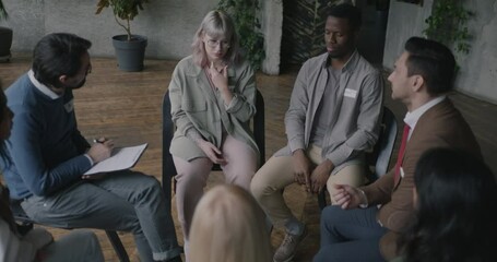 Stressed young woman sharing grief with group getting support of community at therapy session. Communication and psychology concept.