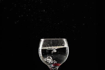 A glass of wine with water and grapes inside.