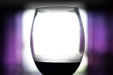 Silhouette of a glass goblet with red wine against the light.