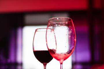 Silhouette of two glass glasses with red and white wine inside on a wooden table, indoors.