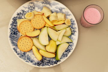 Plate of food with banana, apple, pear, biscuit, cheese and yogurt. Healthy breakfast.