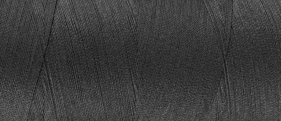 Texture of black color threads in spool close up, macro. Wide banner, header of sewing threads...