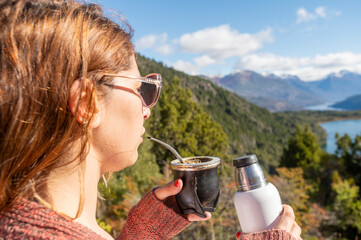 Beautiful lady enjoys a delicious mate with yerba during her vacation in Bariloche, surrounded by beautiful landscapes of mountains and lakes, Argentina.