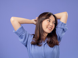 Portrait of an Indonesian Asian woman, wearing a blue shirt, smiling with her hands behind her...