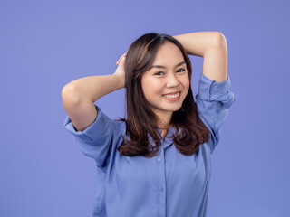 Portrait of an Indonesian Asian woman, wearing a blue shirt, smiling with her hands behind her...