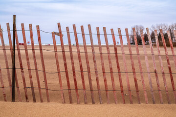 background red brown snow fence with vertical laths on a brown sand beach close up 