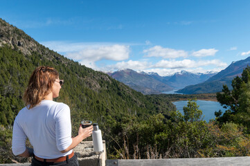 Beautiful lady enjoys a delicious mate with yerba during her vacation in Bariloche, surrounded by beautiful landscapes of mountains and lakes, Argentina.