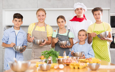 Group portrait of a male chef and teenagers in the kitchen