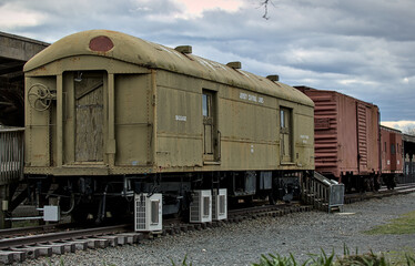 old rusty railroad train car next to wooden ramp (abandoned antique rail travel) overgrown,...
