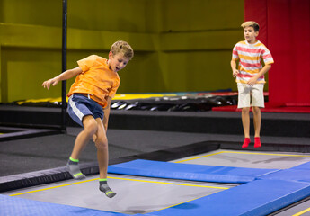 Happy boy jumping on trampoline park in sport center