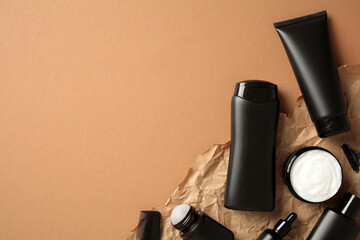 Black bottles with men's hair care products on art paper on a brown background.