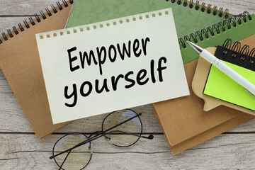 EMPOWER YOURSELF different notepads on the table. text on the page near the glasses - obrazy, fototapety, plakaty