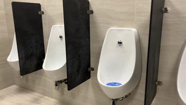 Rows of modern urinals with a sensor WC flush in a public men's room