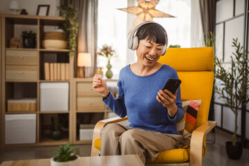 Mature japanese woman with headphones listen music on mobile phone
