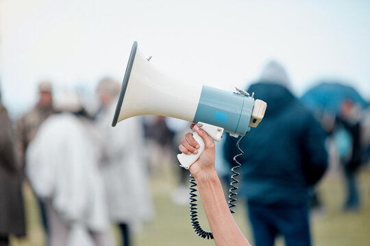 Hand, megaphone and protest with crowd of people with human rights, voice and solidarity at park. Person, bullhorn and community with call to action, sound and rally for change, justice or government