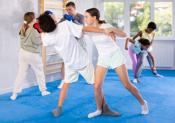Fototapeta premium Girls and boys learns to do power grip with trainer during a self-defense lesson in the gym