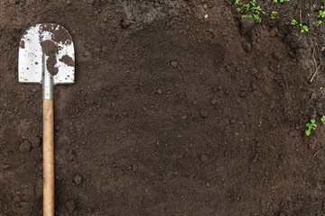 Brown soil ground texture background with copyspace and shovel on garden bed in farm garden....