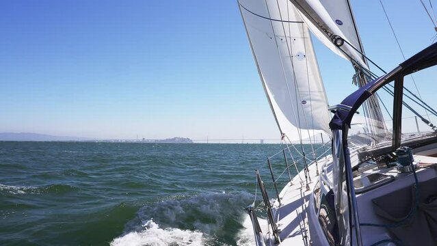 Sailing down the San Francisco bay on a small yacht in California near a Golden Gate bridge and Alcatraz prison island and San Francisco downtown on the horizon. Day at the sea. Sailing concept. 
