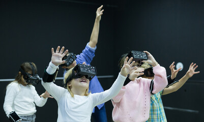 Enthusiastic glad smiling children in virtual reality glasses in quest room