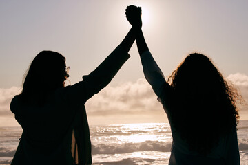 Ocean, silhouette and people holding hands with freedom, friendship and bonding for success,...