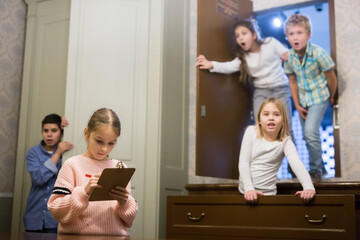 Focused tween girl having fun with her friends in quest room, trying to solve riddles