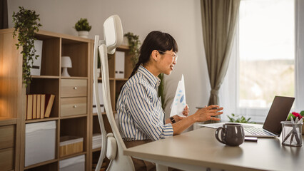 Mature japanese woman hold document and have consultation via video call