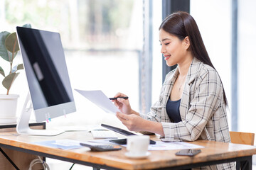 
Portrait of an Asian businesswoman smiling while sitting at her desk.doing planning analyzing the financial report, business plan investment, finance analysis concept.