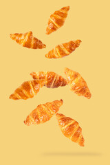 Falling fresh croissant on yellow background. - 794545428
