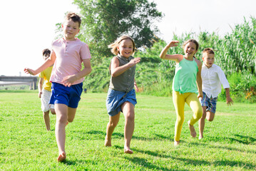 Group of five happy children who are jogging in a park on a sunny day