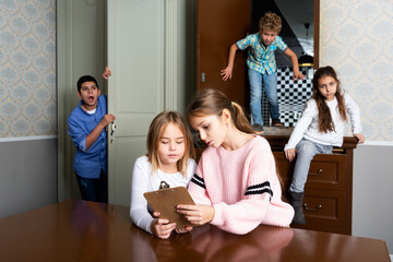 Two interested preteen girls trying to find solution of riddles in quest room