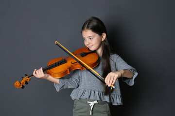 Preteen girl playing violin on black background