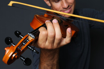 Man playing violin on black background, closeup