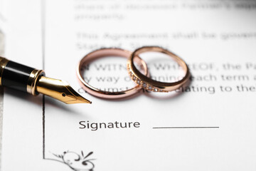 Marriage contract, fountain pen and wedding rings on table, closeup