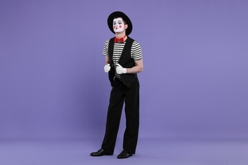 Funny mime artist in hat posing on purple background