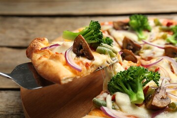 Taking piece of delicious vegetarian pizza at wooden table, closeup