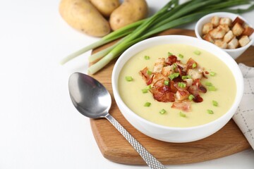 Tasty potato soup with bacon, green onion and croutons in bowl served on white table, space for text