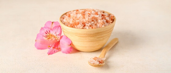 Wooden bowl with sea salt and orchid flower on light background