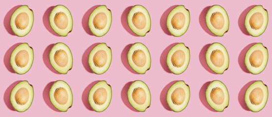 Many halves of fresh ripe avocados on pink background. Pattern for design