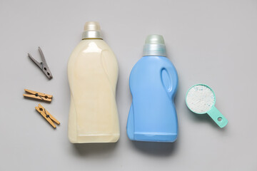 Different laundry detergents with clothespins on grey background