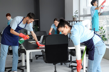 Team of young janitors cleaning in office