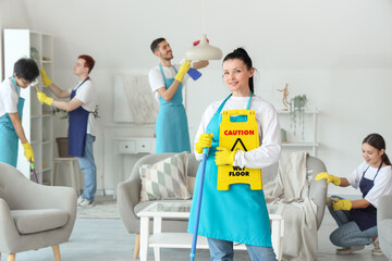 Female janitor with mop and caution sign in room