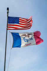 American and State of Iowa flags proudly waving and fluttering on a strong wind