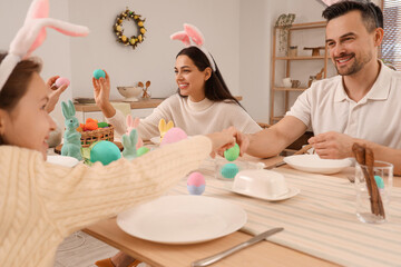 Happy family with painted eggs in dining room on Easter Day