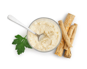 Horseradish sauce in glass bowl with spoon and horseradish root on white background. Top view