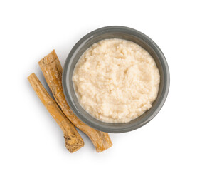 Horseradish sauce in grey ceramic bowl with horseradish root on white background. Top view