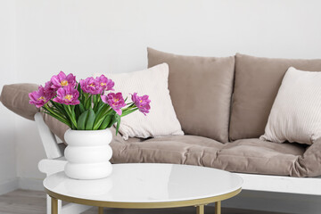 Vase with pink tulips on table in light living room