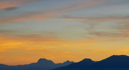 Luminoso tramonto arancio e ocra sopra le montagne italiane