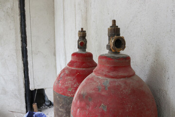 Photo of a red gas cylinder for welding iron outside a building under construction