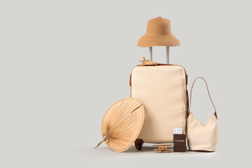 Beige suitcase with hat and bag on grey background. Travel concept