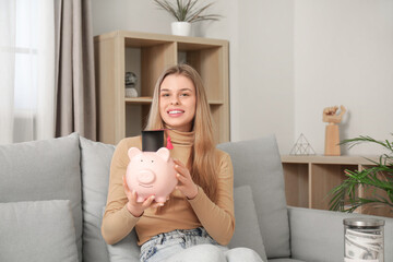 Female student holding piggy bank in graduation hat in room. Concept of savings for education
